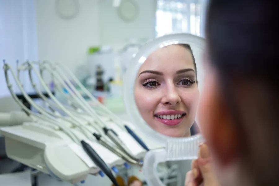 Woman checking her smile in a dental mirror
