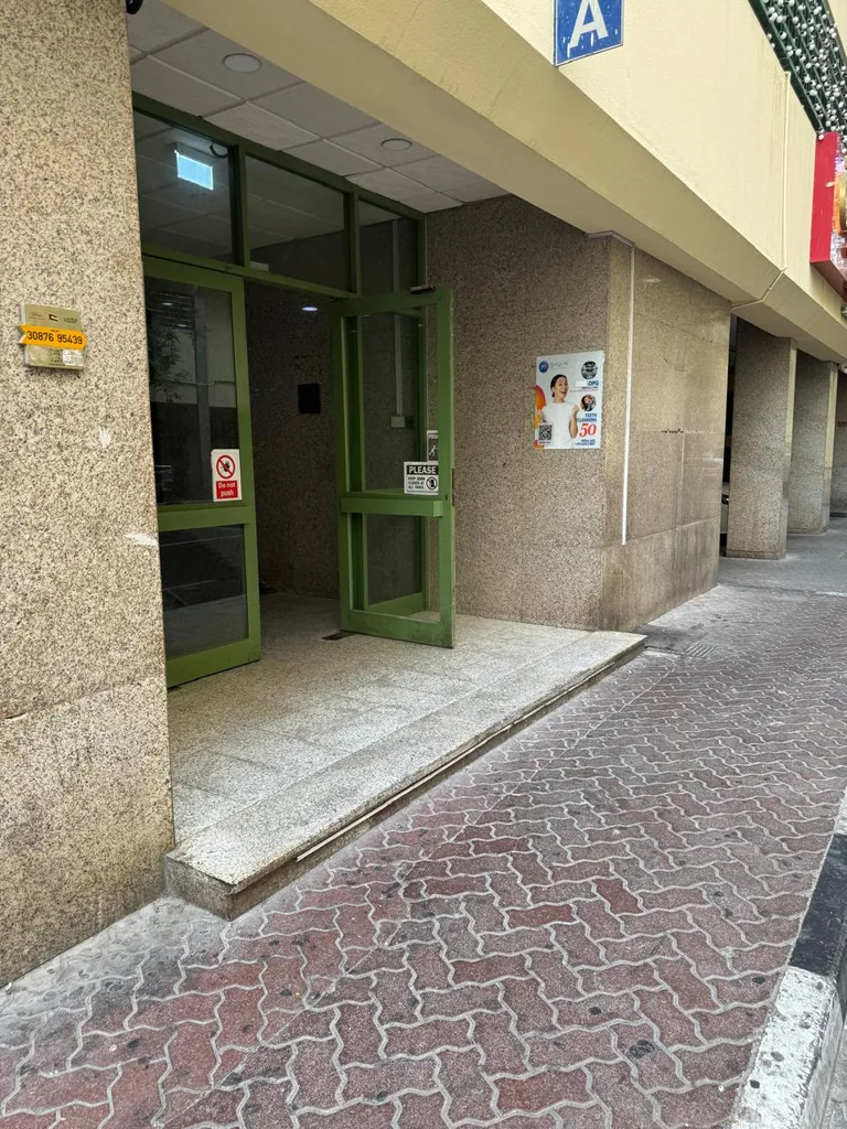 Block A entrance with green glass doors and the blue A sign, Al Owais Building